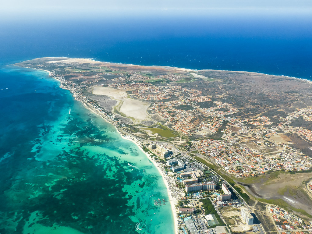 Aruba Fast Facts – Aerial Overview of One Happy Island Aerial view of Aruba island with turquoise Caribbean waters, white-sand beaches and the dry inland landscape