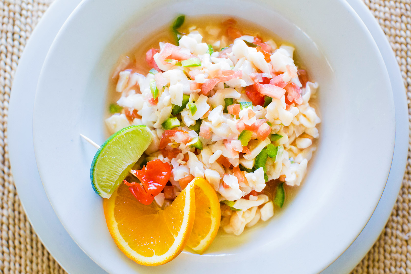 Bahamas Food & Drinks – Best Local Cuisine & Island Flavors Traditional Bahamian conch salad with lime, orange slices, peppers and fresh seafood flavors
