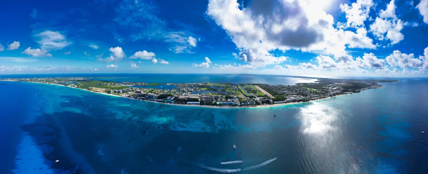 Cayman Islands Travel Guide – Grand Cayman Aerial View Aerial panoramic view of Grand Cayman with turquoise waters, coral reefs and the coastline of Seven Mile Beach