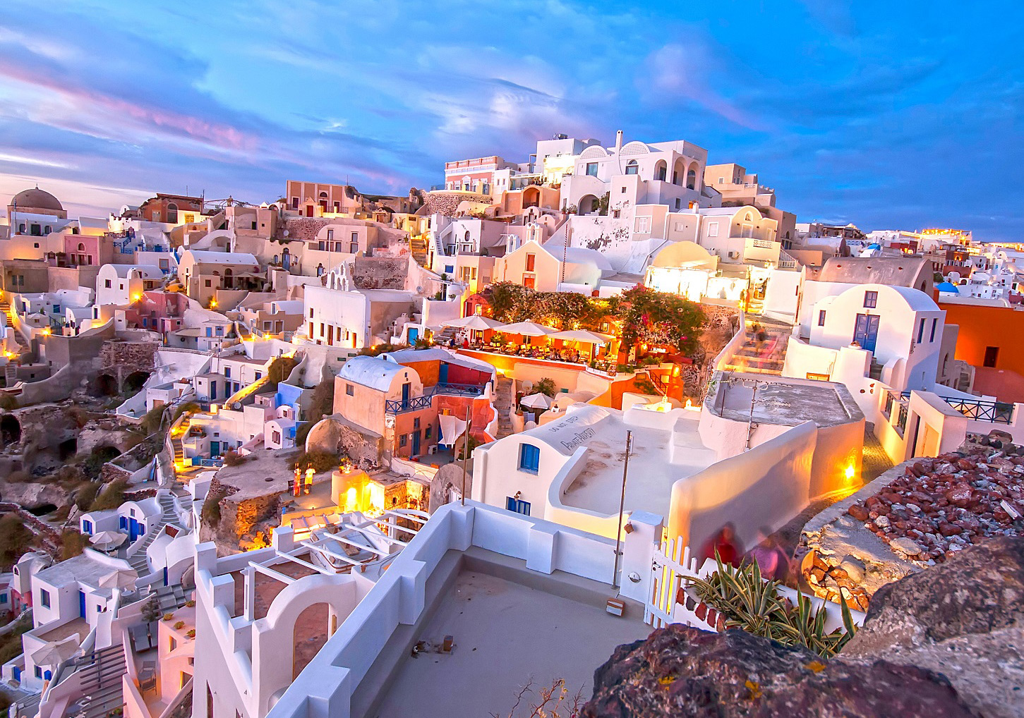Nightlife in Greece – Santorini Evening Atmosphere Evening view of Santorini in Greece with illuminated white buildings and blue-hour sky
