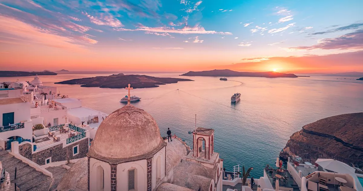 Greece Travel Guide – Santorini Caldera Sunset View Evening view of Fira caldera in Santorini with whitewashed buildings and the Aegean Sea at sunset