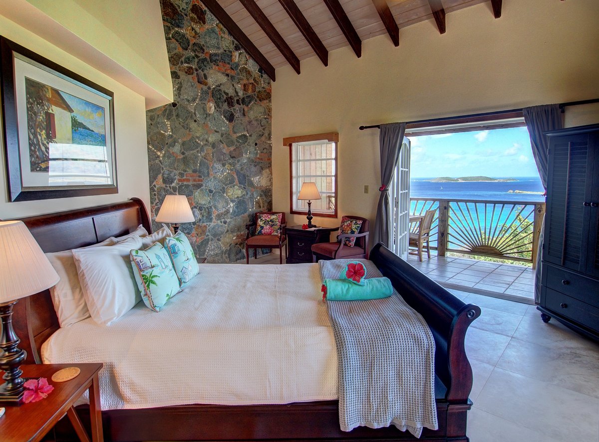 Ocean-View Rooms – Comfort with a View Bright bedroom with open doors to a terrace overlooking the ocean in the Virgin Islands