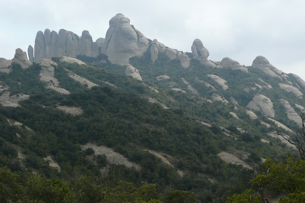 Rock formations rising above wooded slopes in the Montserrat mountain landscape Rock formations rising above wooded slopes in the Montserrat mountain landscape