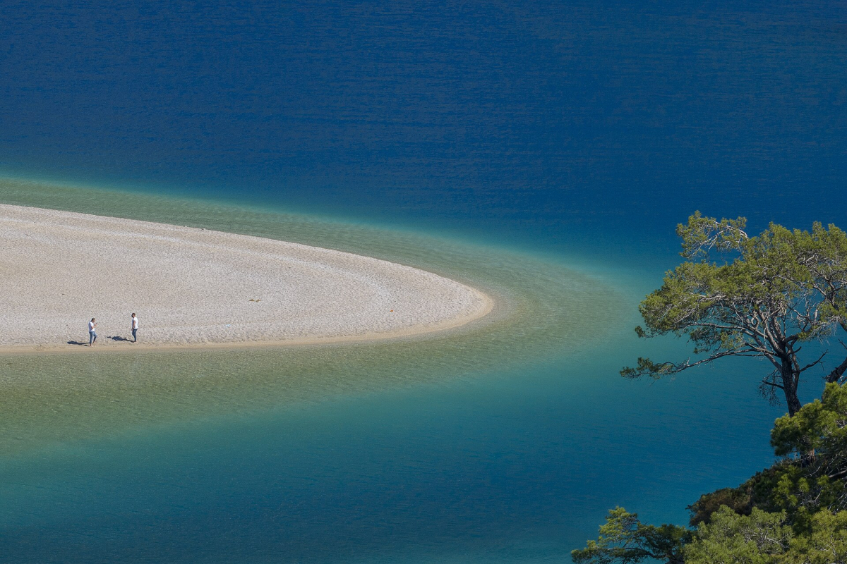 Pale beach curving into the blue water of Ölüdeniz lagoon Pale beach curving into the blue water of Ölüdeniz lagoon