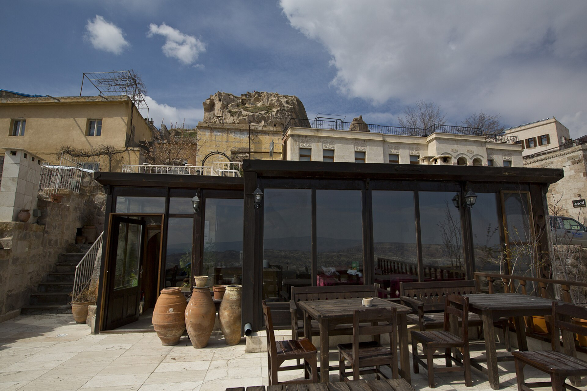 Tables on the Taka Ev hotel terrace beneath the rocky buildings of Uçhisar Tables on the Taka Ev hotel terrace beneath the rocky buildings of Uçhisar