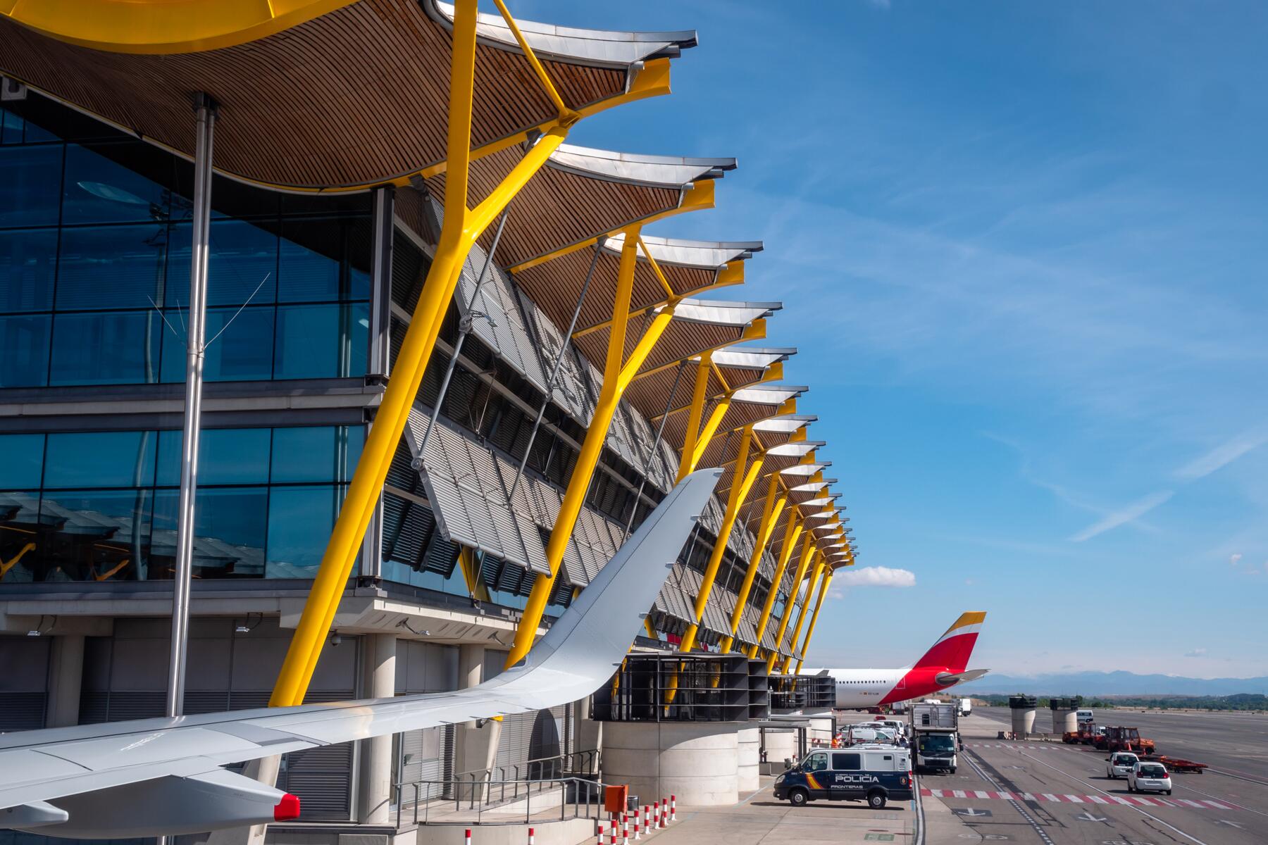 Madrid Airport Guide – Adolfo Suárez Madrid–Barajas (T4 & Connections) Adolfo Suárez Madrid–Barajas Airport Terminal 4 with yellow beams and aircraft wing on the apron
