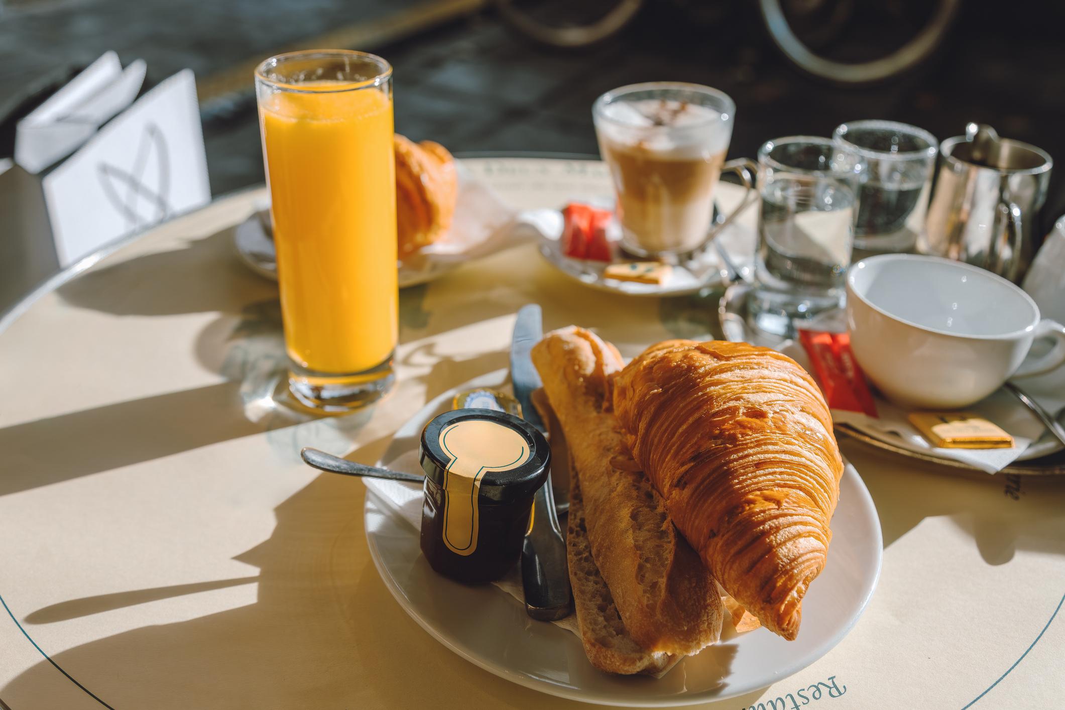 Paris Food & Drinks Guide Traditional French breakfast with croissant, baguette, coffee, and orange juice
