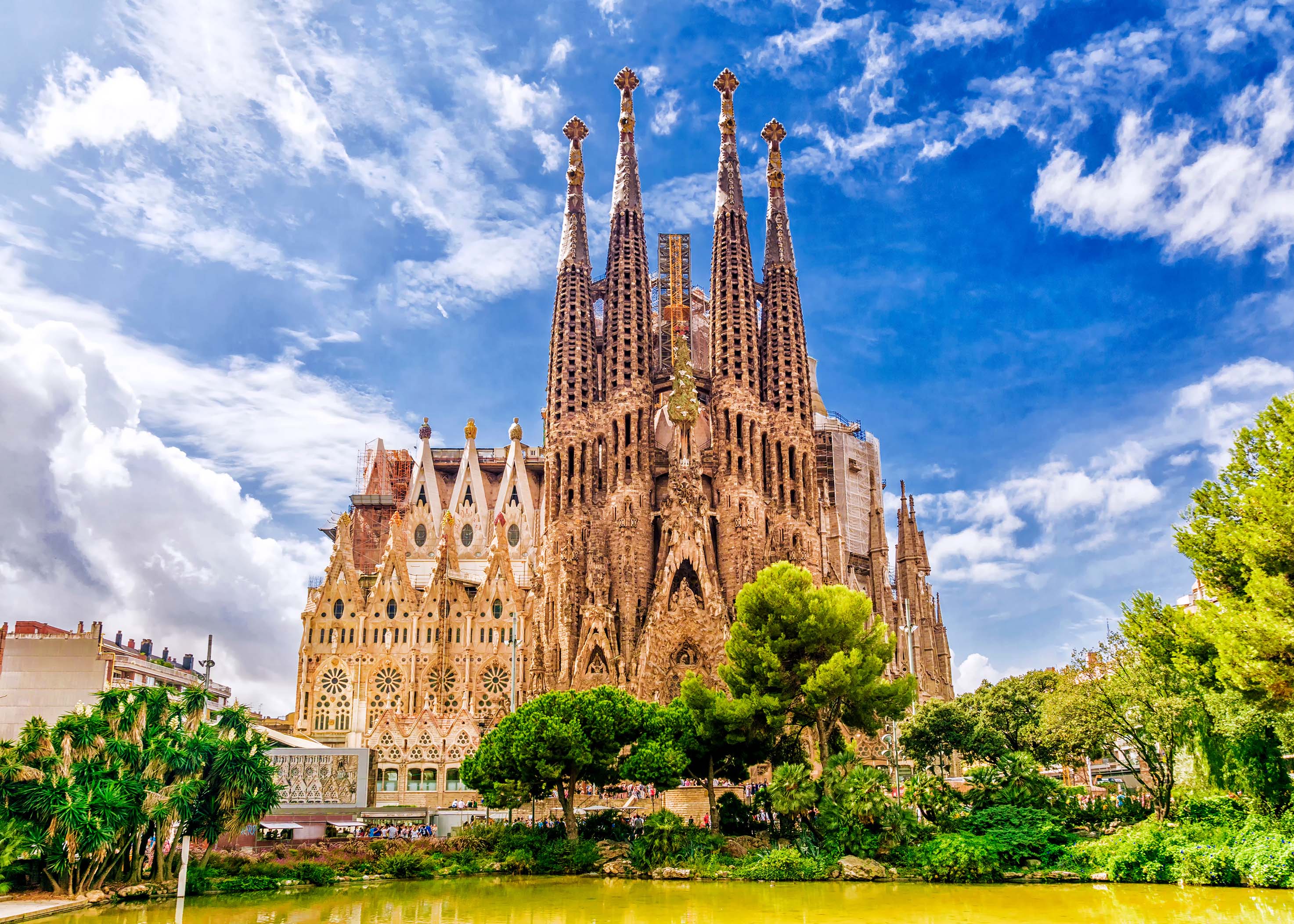 Sagrada Família – Barcelona’s most iconic Gaudí masterpiece Sagrada Família basilica in Barcelona viewed from Plaça de Gaudí park with trees and reflection pool