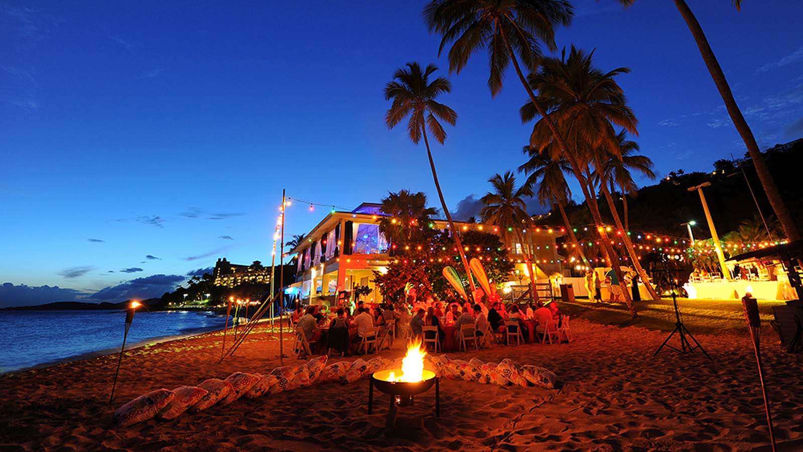 Nightlife in the Virgin Islands – Beach Bars, Live Music & Evening Vibes Beachfront nightlife in the Virgin Islands with palm trees, string lights and a lively evening atmosphere